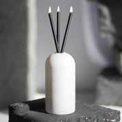 white vase with three lit black everlasting candle co wicks inside