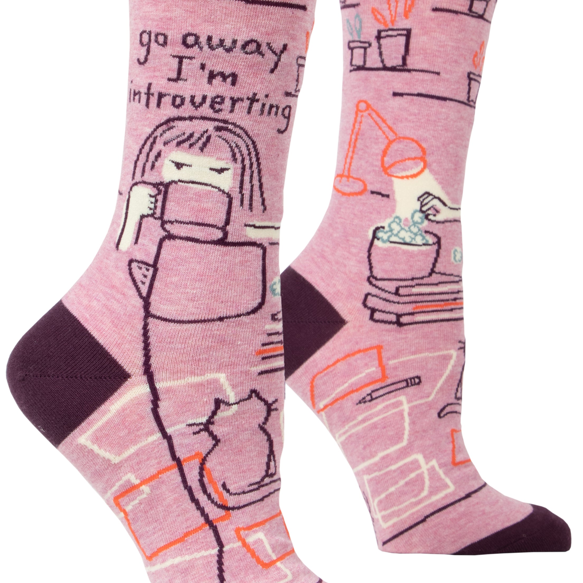 pink socks with cartoon of person as desk with popcorn books, lamp cat and plants on ankle it says go away i'm introverting 