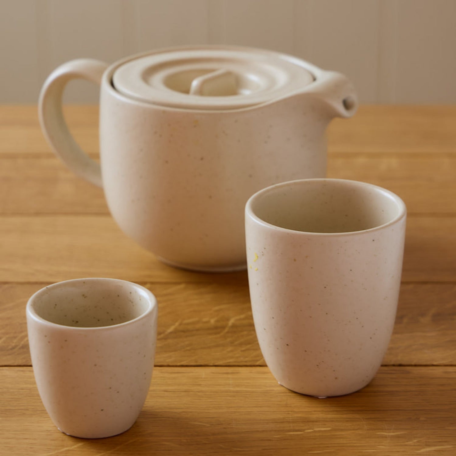 Set of ceramic teapot and two cups on a wooden surface