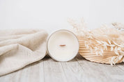 Candle and dried plants on a wooden surface with a light background