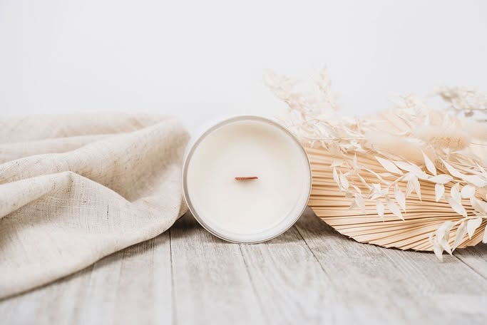 Candle and dried plants on a wooden surface with a light background