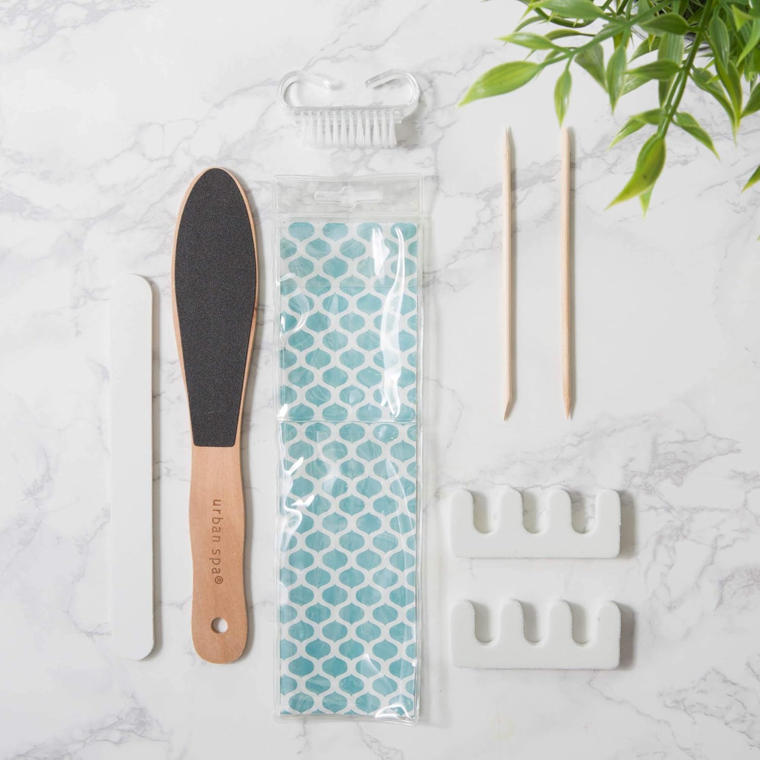 Pedicure tool set with a file, pedicure brush, and packaging on a marble surface.
