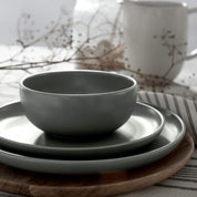 Set of green ceramic dishes on a wooden board with a blurred background