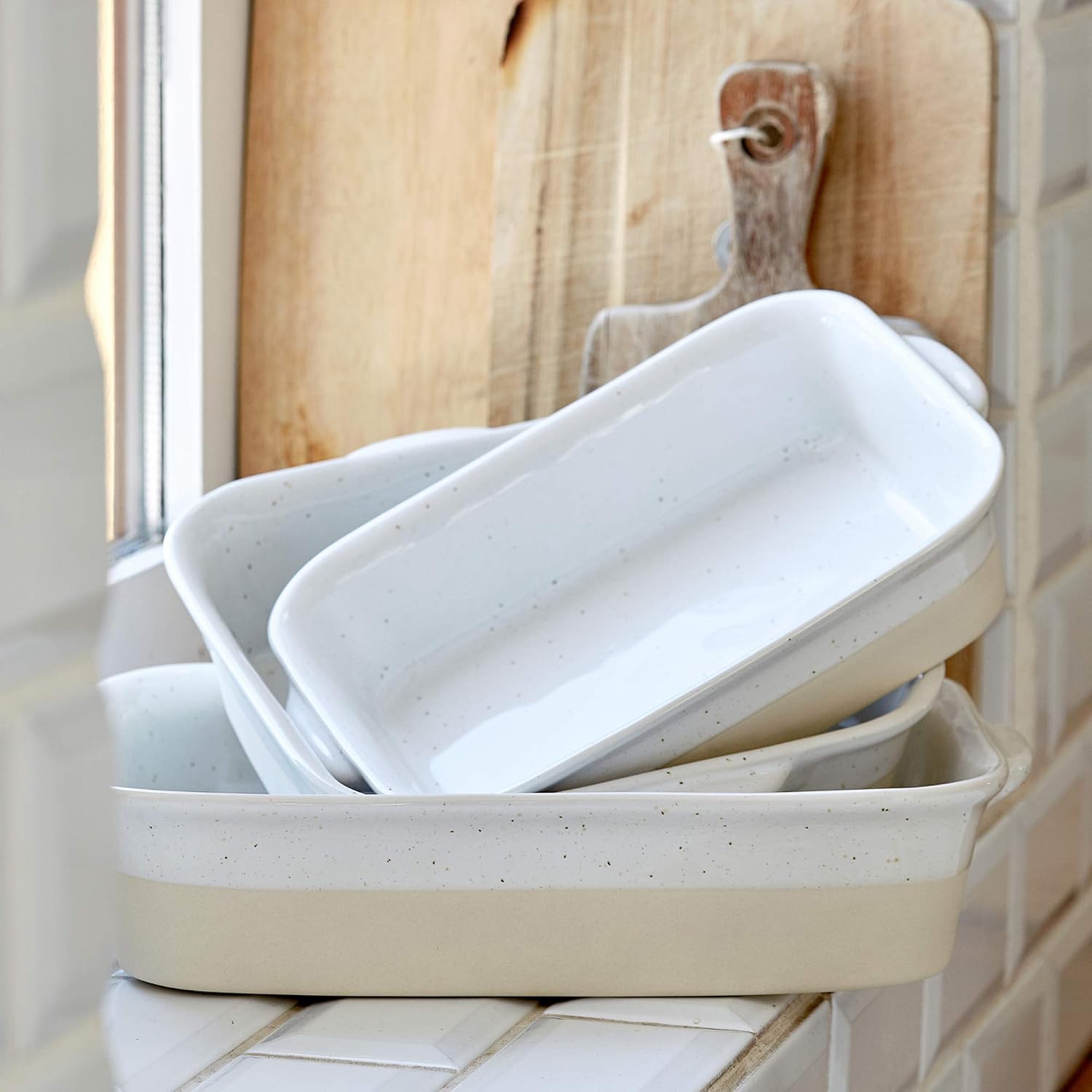 Set of white ceramic trays stacked on a tiled surface