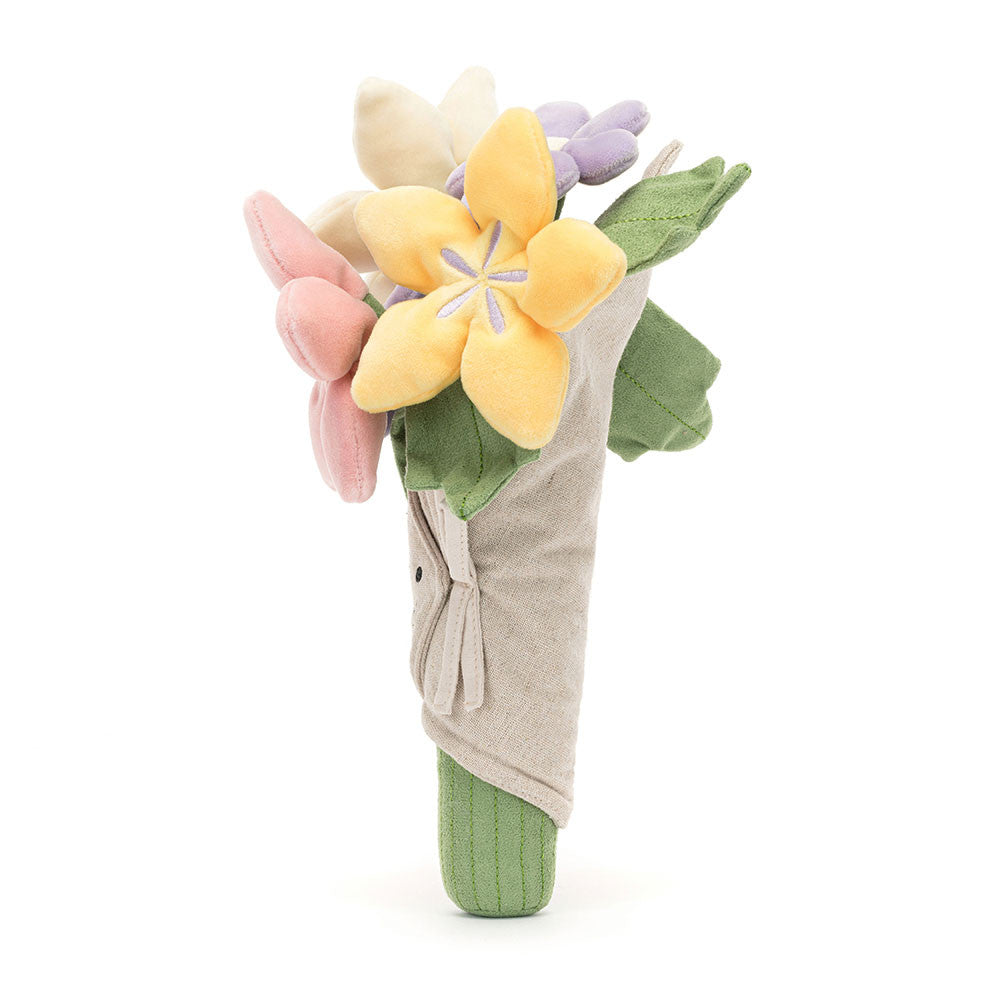 side view of Plush jellycat  bouquet of pink purple white and yellow flowers with a smiling face on a white background