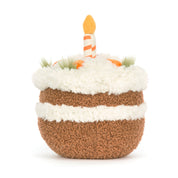 Plush toy carrot cake with smiling face, little feet and with candles on a white background