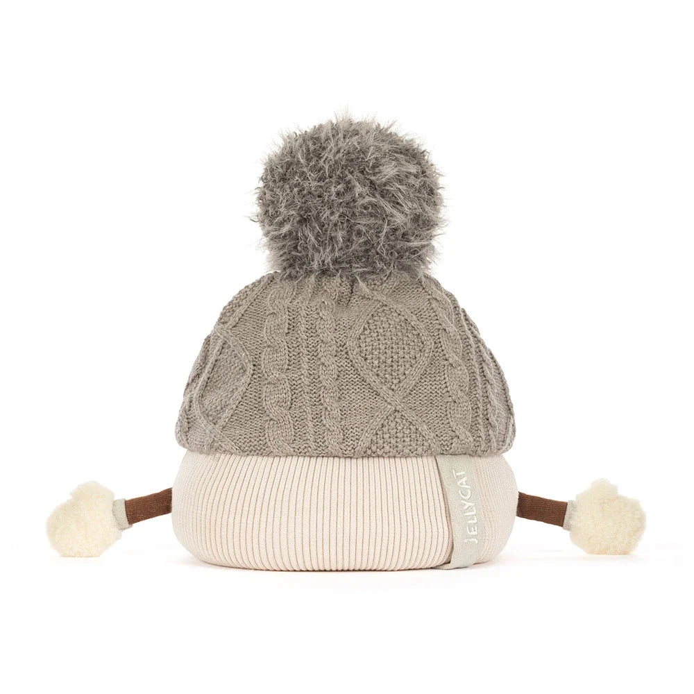 backview of A plush toy toque by jellycat with a gray cable-knit top, a cream ribbed bottom, a gray pom-pom, and small fabric hands and feet, shown on a white background.
