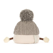 backview of A plush toy toque by jellycat with a gray cable-knit top, a cream ribbed bottom, a gray pom-pom, and small fabric hands and feet, shown on a white background.