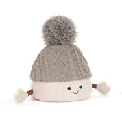 A plush toy toque by jellycat with a gray cable-knit top, a cream ribbed bottom, a gray pom-pom, and small fabric hands and feet, shown on a white background.