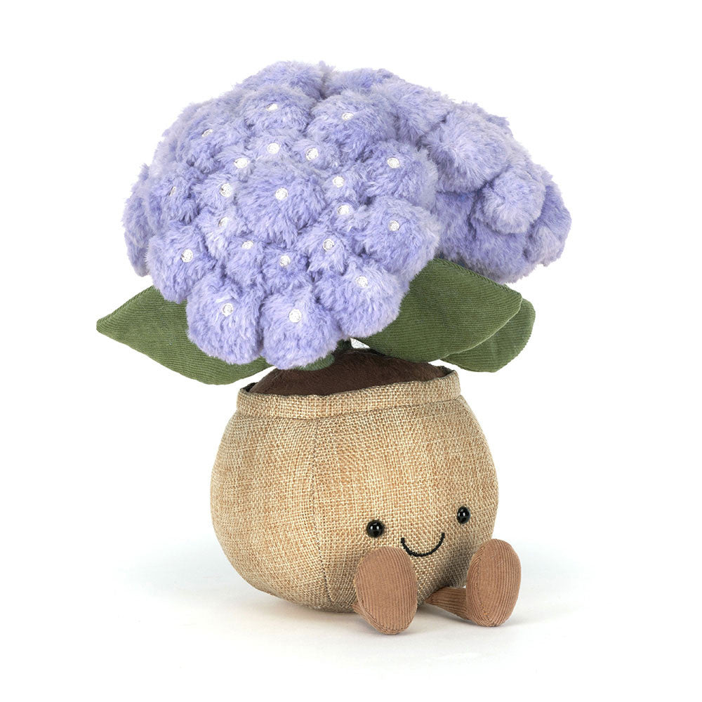 Plush toy purple hydrangea flower with green leaves in beige pot with a smiling face on a white background