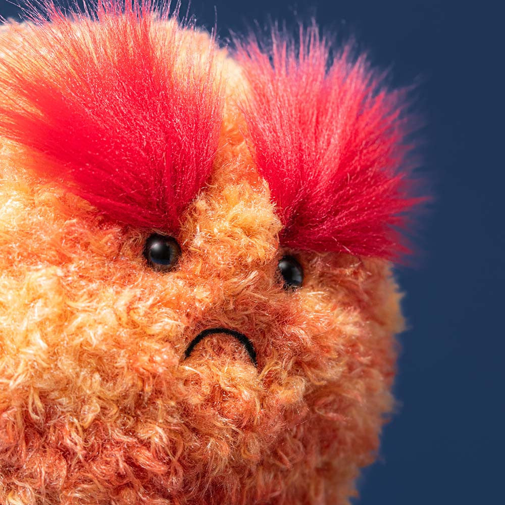 detail close up shot of mars plush toy's face with busy red tall eye brows, orange fur body and sad frown on white background