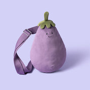 Plush bum bag purse by jellycat shaped like an eggplant with a smiling face on a purple background