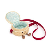 A plush bag shaped like a smiling cake with brown cord feet, black beady eyes and a stitched smile, featuring a cream-colored textured exterior, a light blue patterned fabric lining, and a red shoulder strap, shown on a white background.