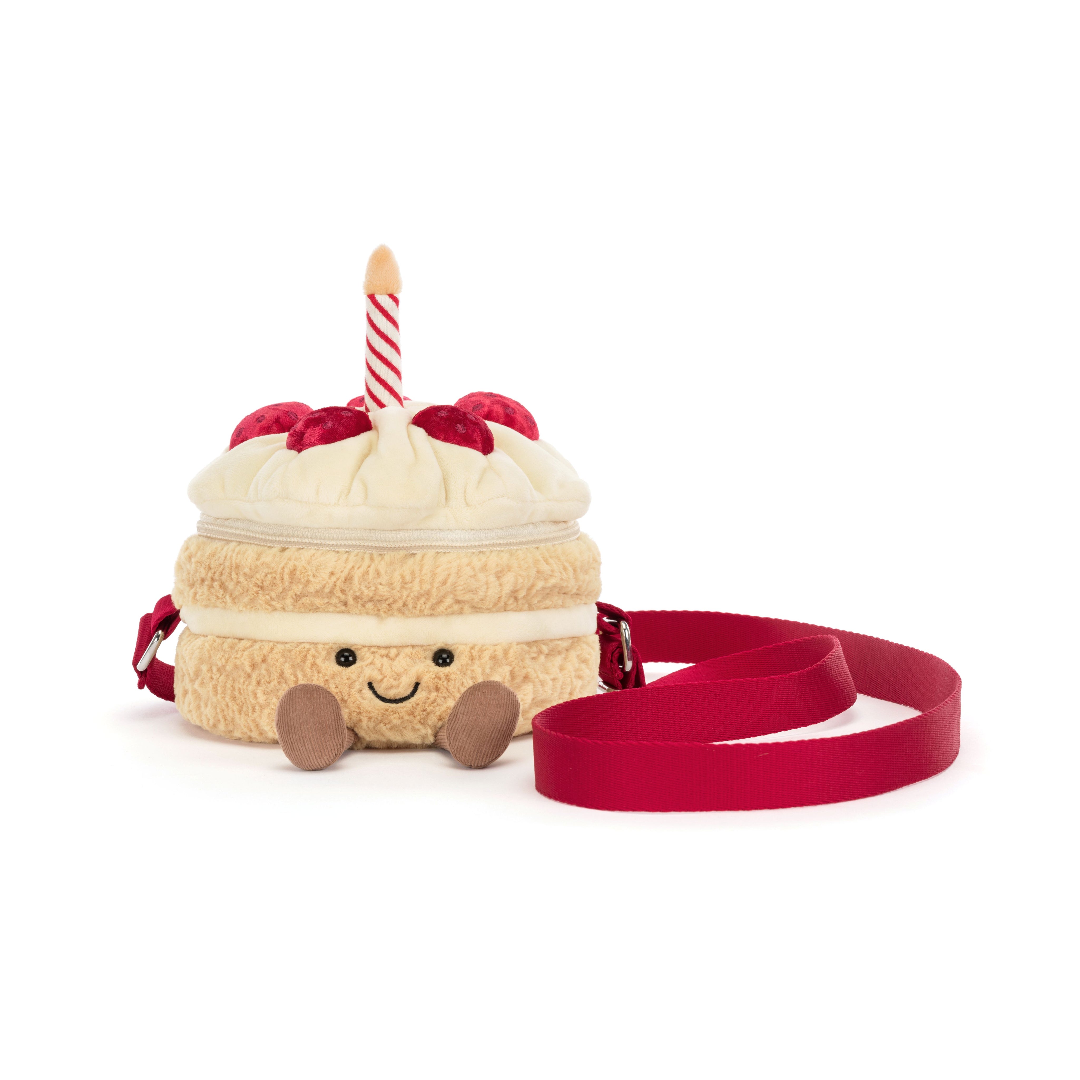 A plush cake-shaped crossbody bag with a cream-colored body, red strawberries, a red-and-white striped candle, and a red strap, photographed on a white background.