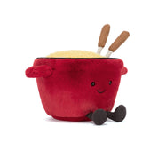 Red jellycat plush fondue pot with a face, cheese inside, and wooden forks sticking out on a white background