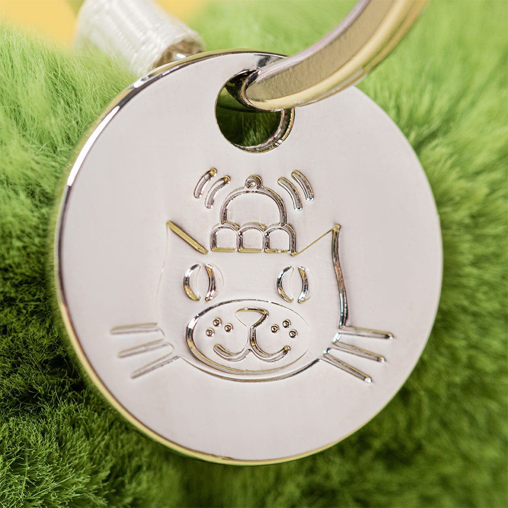 Silver jellycat logo keychain tag on a green textured background