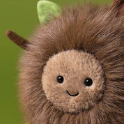 close up of jellycat forest floor with fuzzy fur and leaves and sticks on green background
