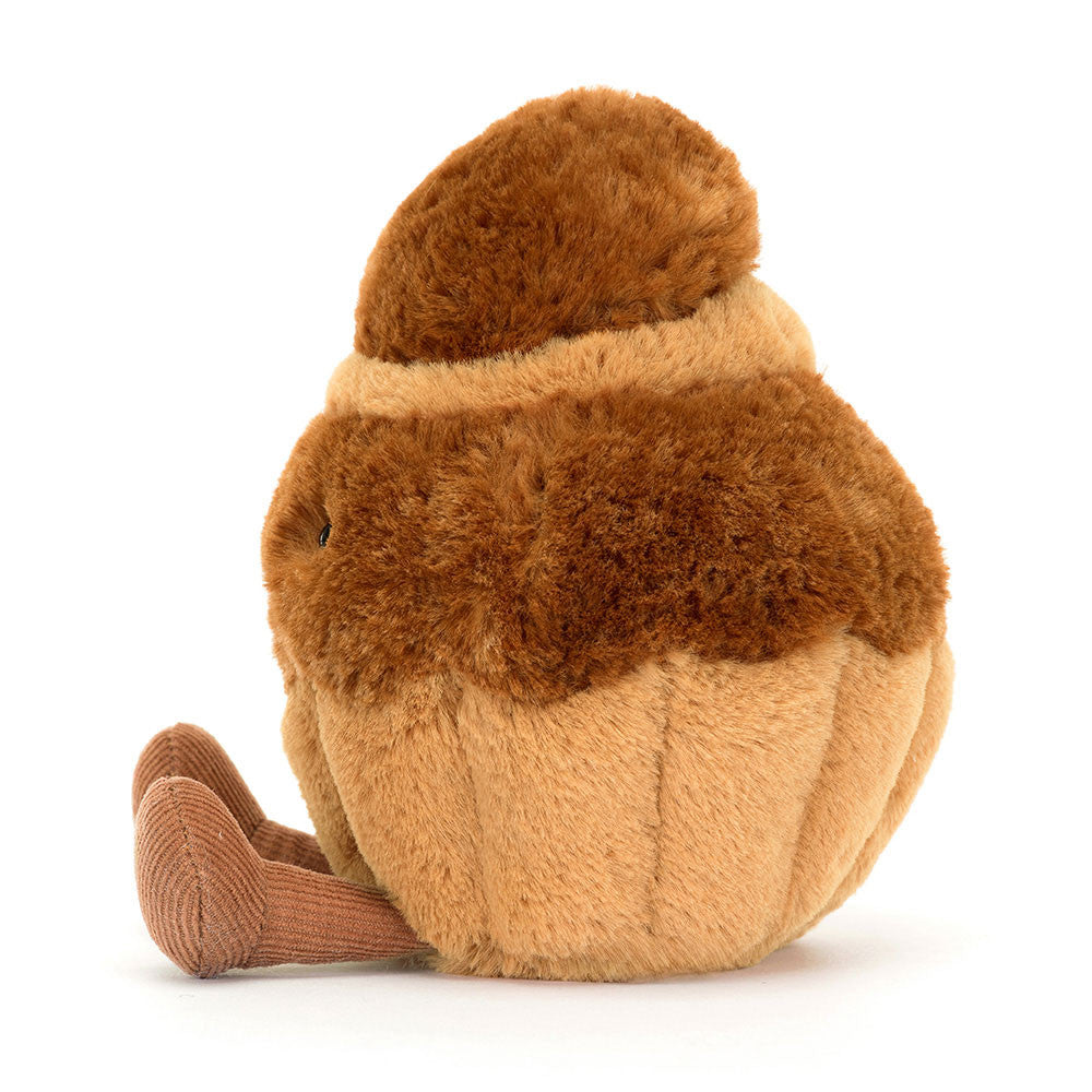 Jellycat plush toy resembling a brown and beige brioche pastry with a smiling face, corduroy legs, and a soft textured surface. side view