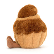 Jellycat plush toy resembling a brown and beige brioche pastry with a smiling face, corduroy legs, and a soft textured surface. side view