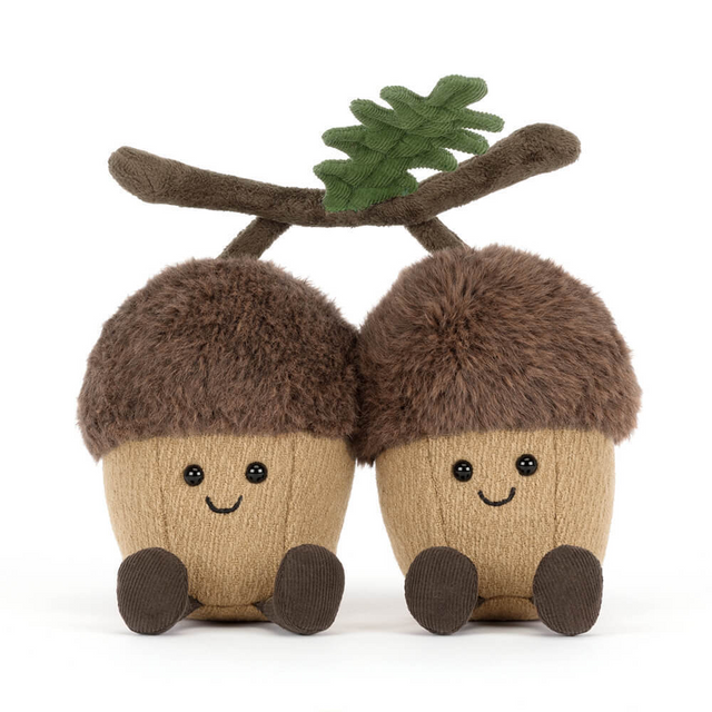 Two jellycat plush acorns with faces and a branch on a white background