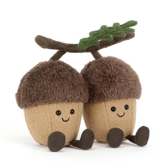 Two jellycat plush acorns with faces and a branch on a white background
