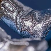 close up detail of shiny silver material with stitched star