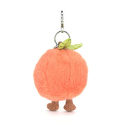 Plush peach-shaped keychain with legs and a stem on a white background