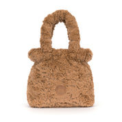 A small brown faux fur handbag with a top handle and a circular embossed logo patch on the backside, shown on a white background.