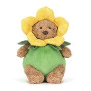 Plush brown bear in green and yellow daffodil flower outfit on white background