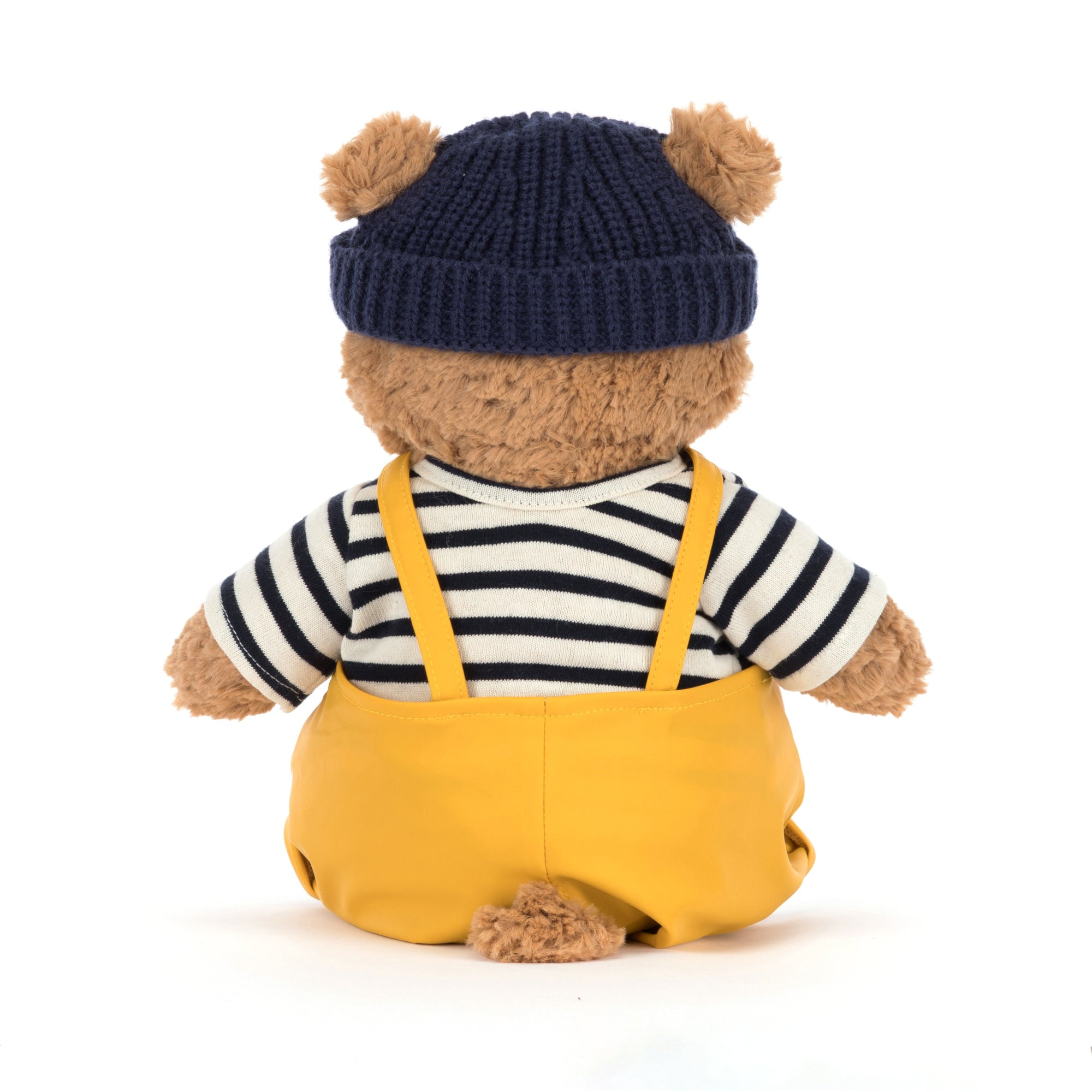 back view of jellycat bartholomew Teddy bear dressed as a sailor wearing a navy hat, striped shirt, and yellow overalls on a white background