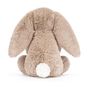 back view of a Plush jellycat bunny holding a birthday cake with a candle on a white background