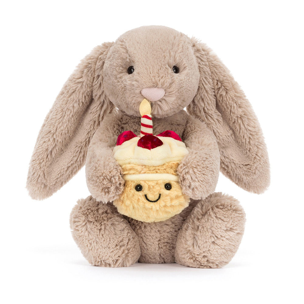 Plush jellycat bunny holding a birthday cake with a candle on a white background