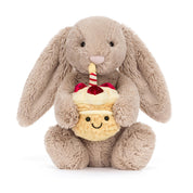 Plush jellycat bunny holding a birthday cake with a candle on a white background