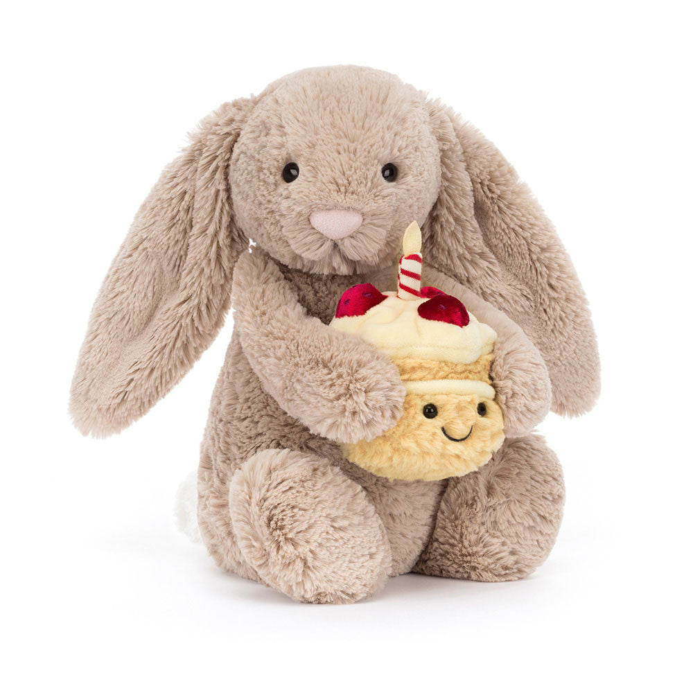 Plush jellycat bunny holding a birthday cake with a candle on a white background