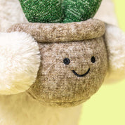 detail shot of smiling put held by plush bunny with yellow background