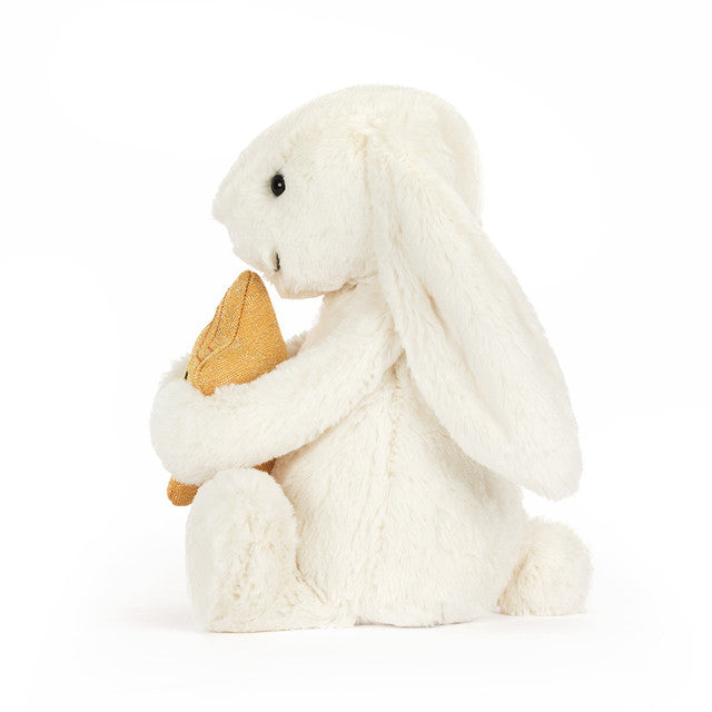 side view of white bunny rabbit plush toy holding yellow star on white background