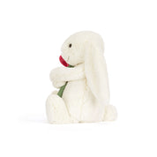 side view of White plush bunny holding a red rose on a white background