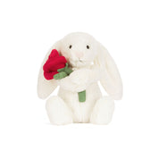 White plush bunny holding a red rose on a white background