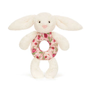 Plush bunny baby rattle toy from jellycat with a floral ring on a white background