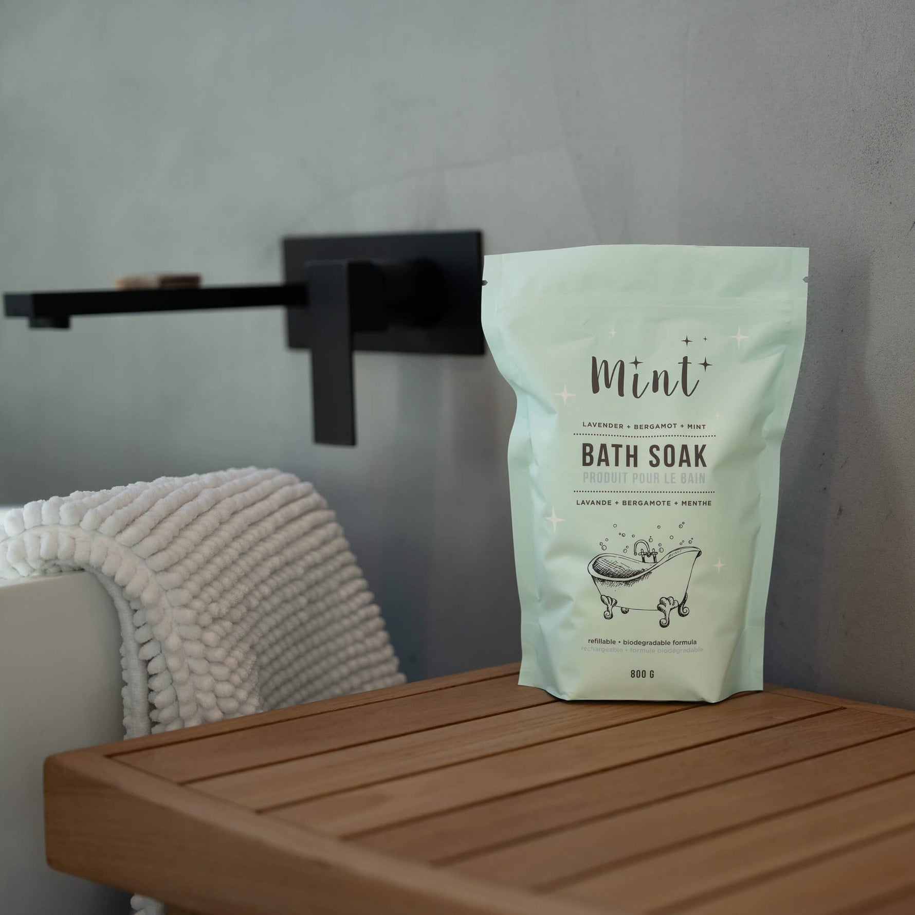 Bag of Mint Bath Soak on a wooden surface with a towel and shelf in the background