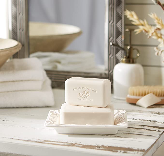 off white bar of soap sitting in dish on a distressed wood counter in bathroom