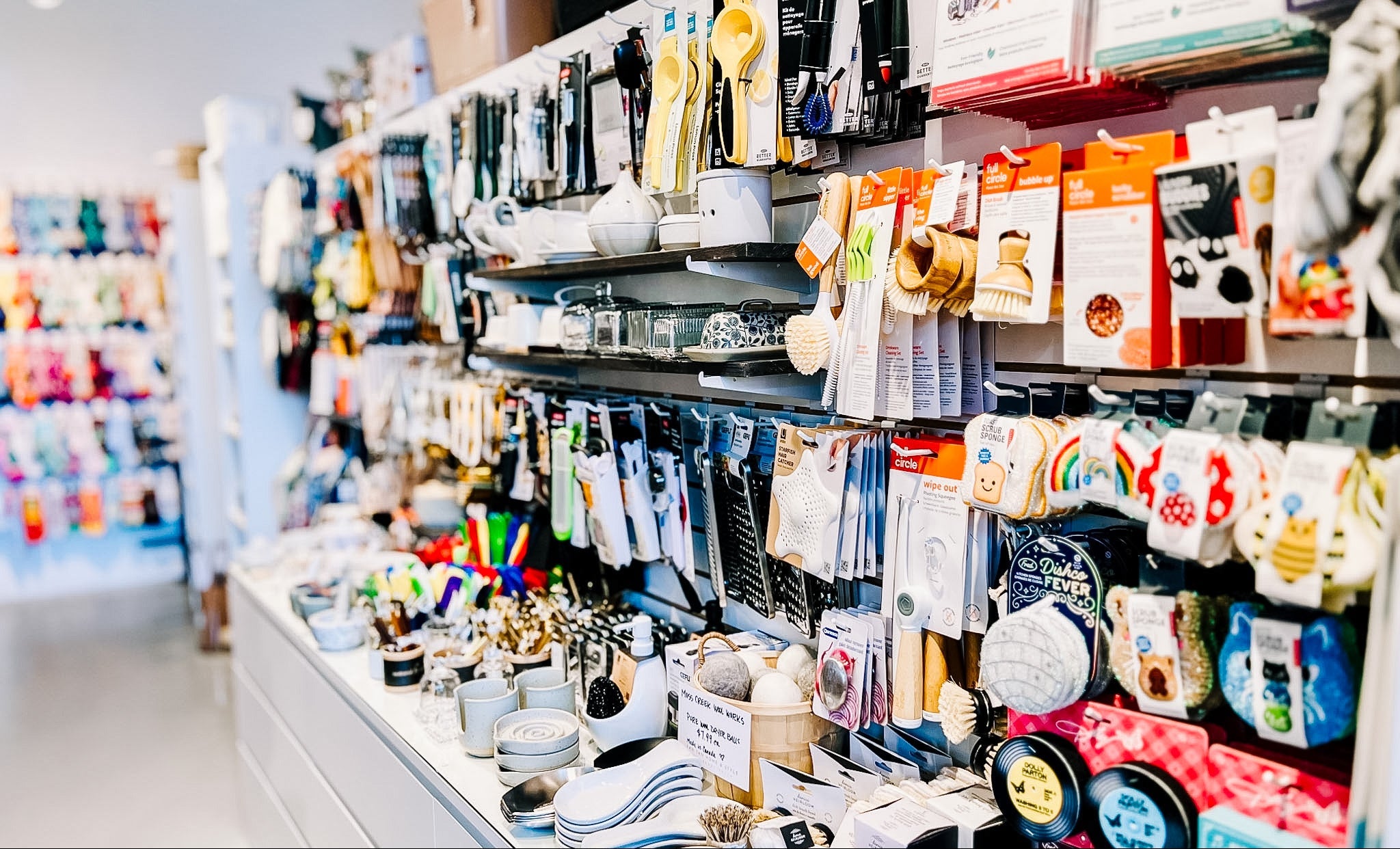 Store interior shelving along a wall above long cupboards showcasing various kitchen items