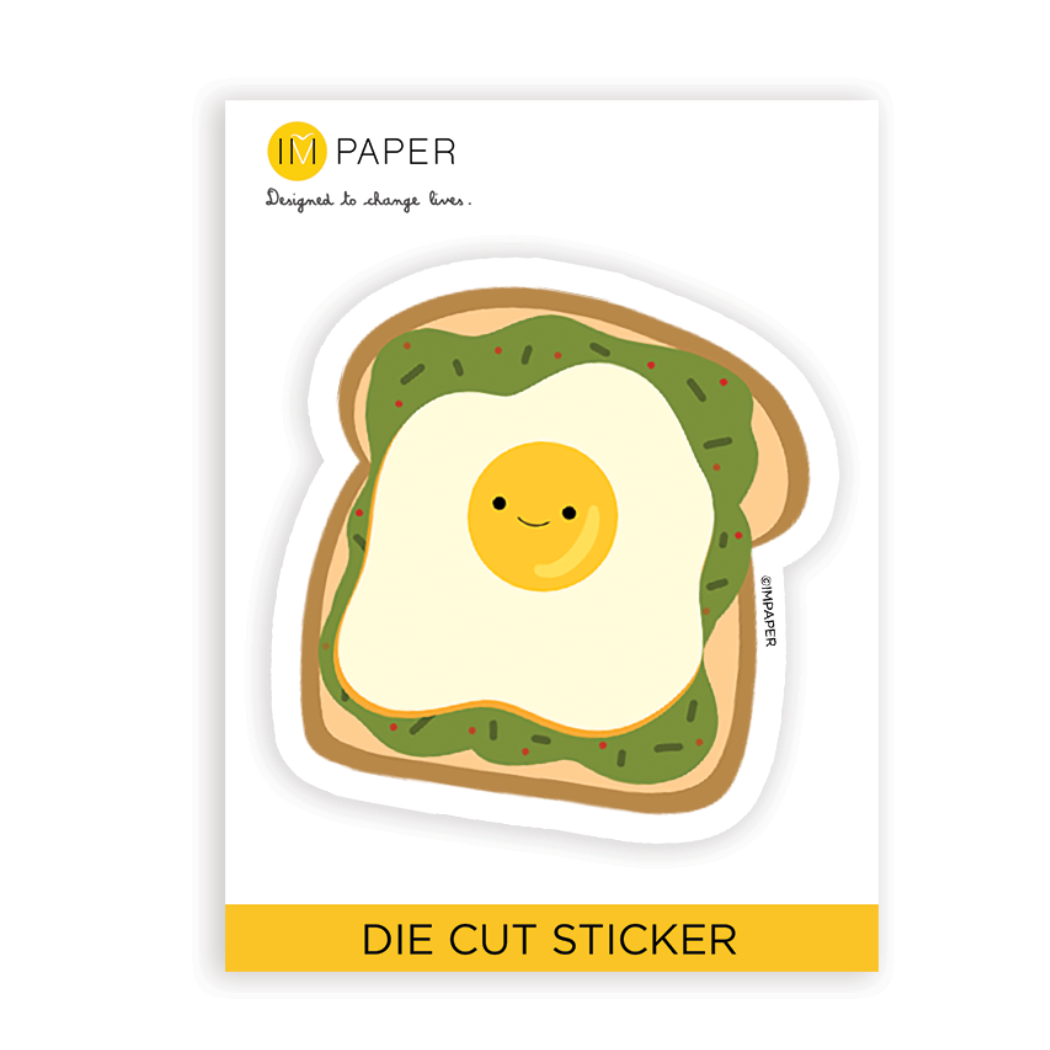 sticker of a smiling fried egg on top of avocado toast text below read "die cut sticker" 