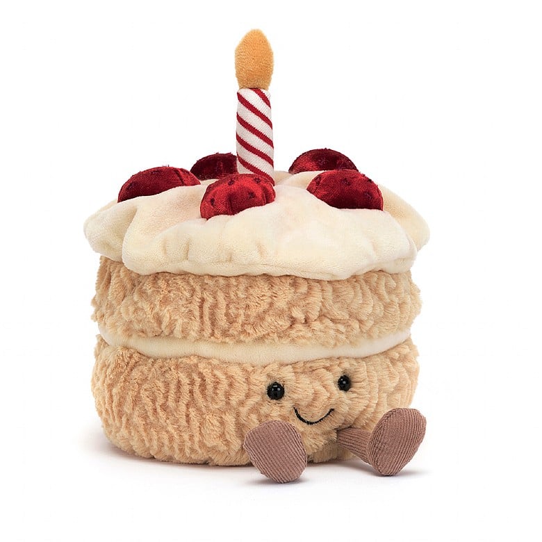 fluffy stuffed plush toy of vanilla birthday cake with red berries, white frosting, candle and black smiley face
