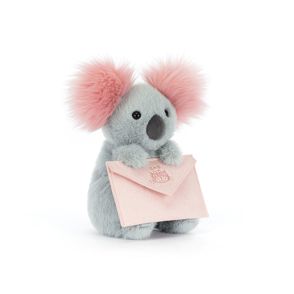 Plush koala toy with pink ears holding a pink card on a white background