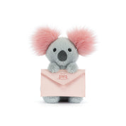 Plush koala with pink ears holding a pink envelope on a white background