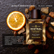 Mistral Black Amber perfume bottle with an orange slice and stones on a dark background