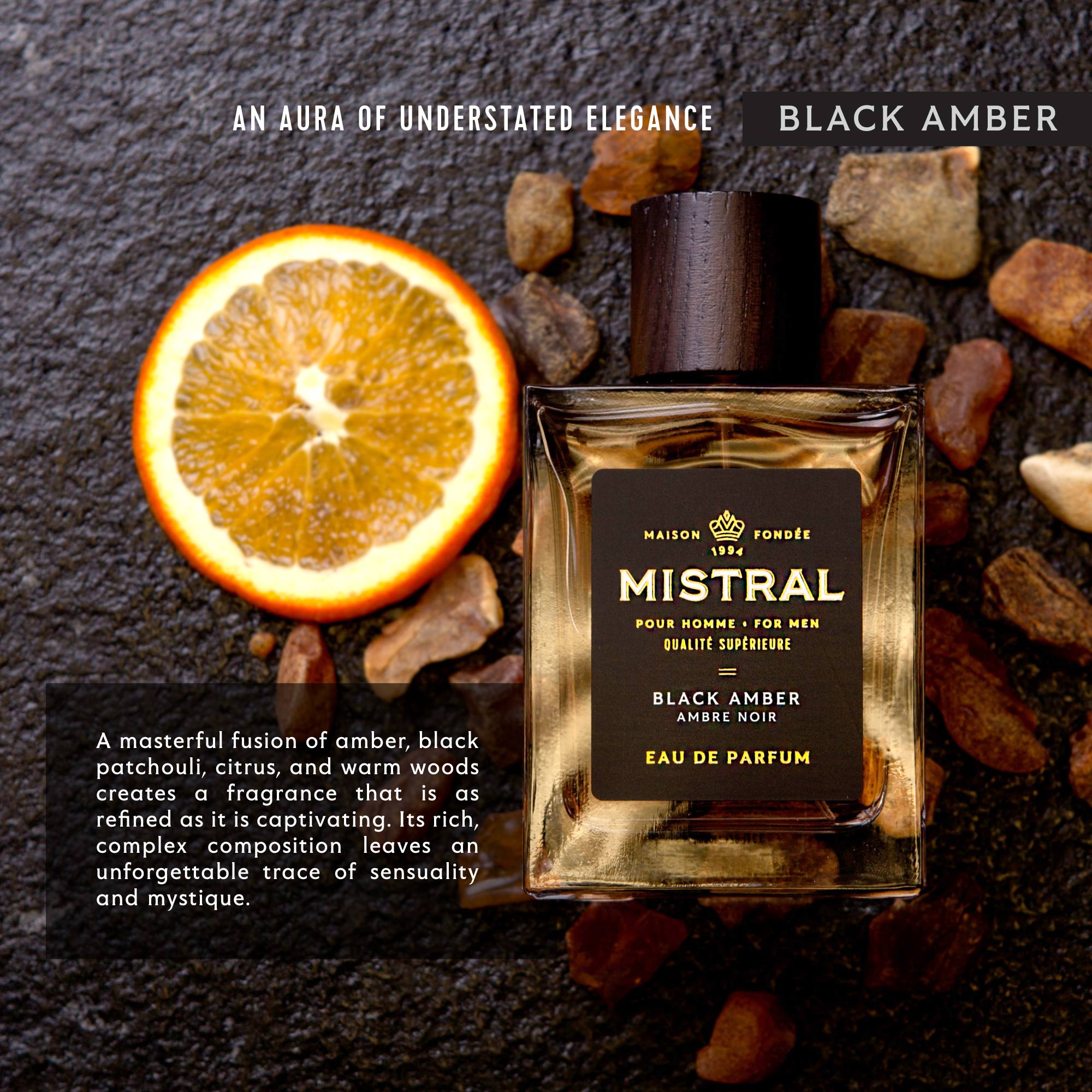 Mistral Black Amber perfume bottle with an orange slice and stones on a dark background