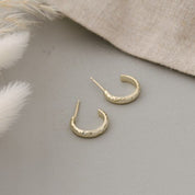 Gold hoop earrings on a gray surface with a neutral background