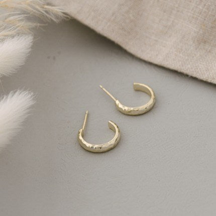 Gold hoop earrings on a gray surface with a neutral background